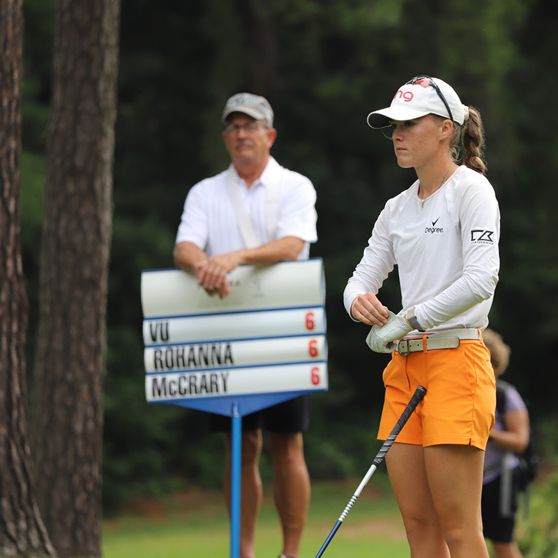 Maddie McCrary waiting to shoot and volunteer holding sign in background